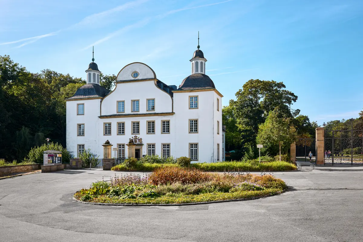 Schloss Borbeck in Essen, ein barockes Gebäude mit weißen Fassaden und einem großen Rundweg davor.