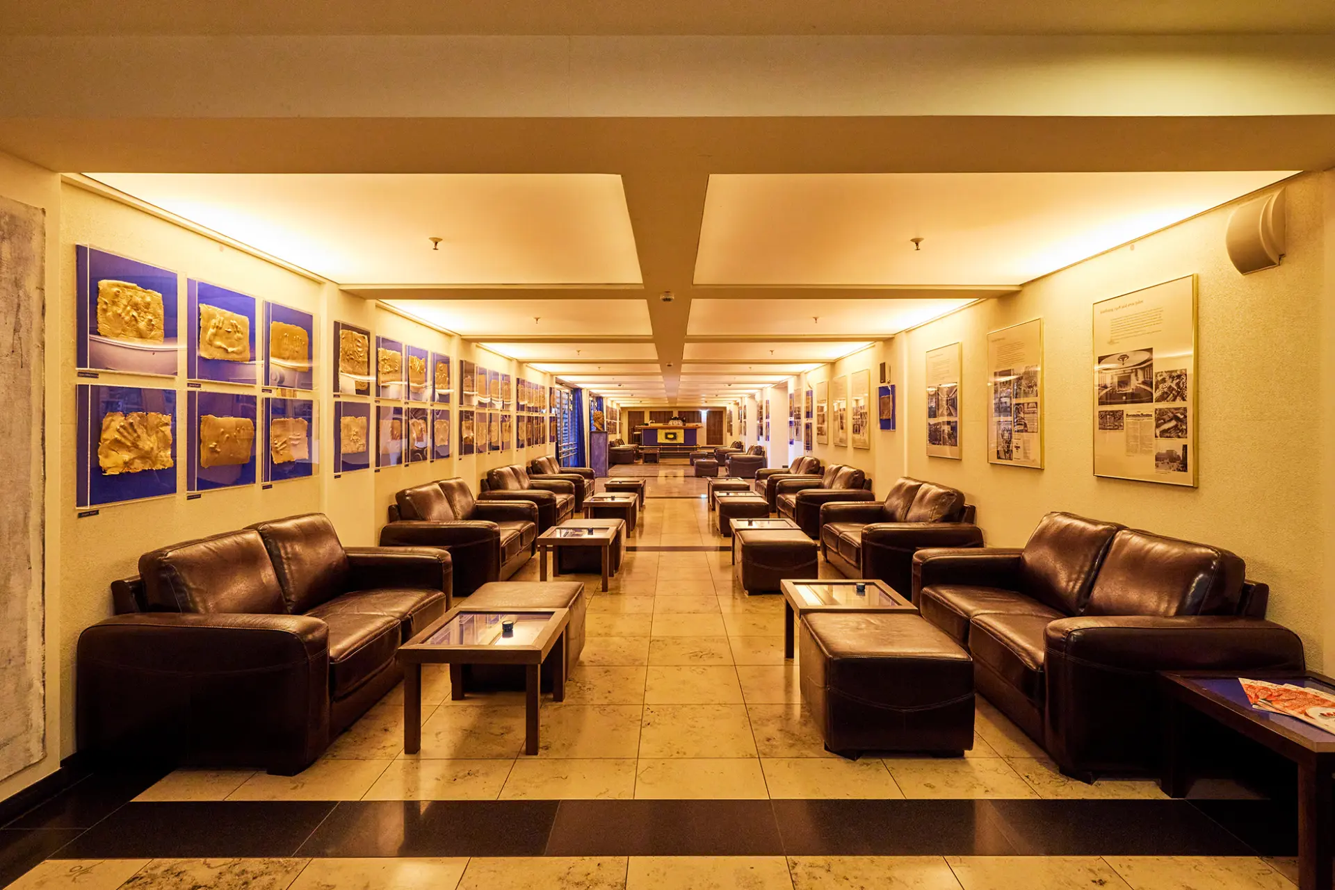 Ein stilvoller, langer Flur mit Ledersofas, modernem Lichtdesign und Kunstwerken an den Wänden.