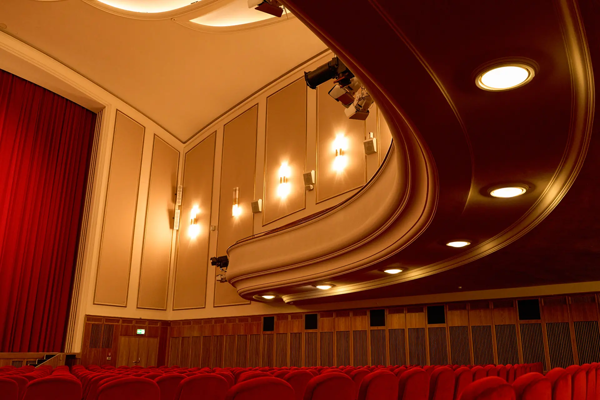 Innenansicht eines Theatersaals mit rotem Samt bestückten Sitzen und kunstvoll gestalteter Decke.