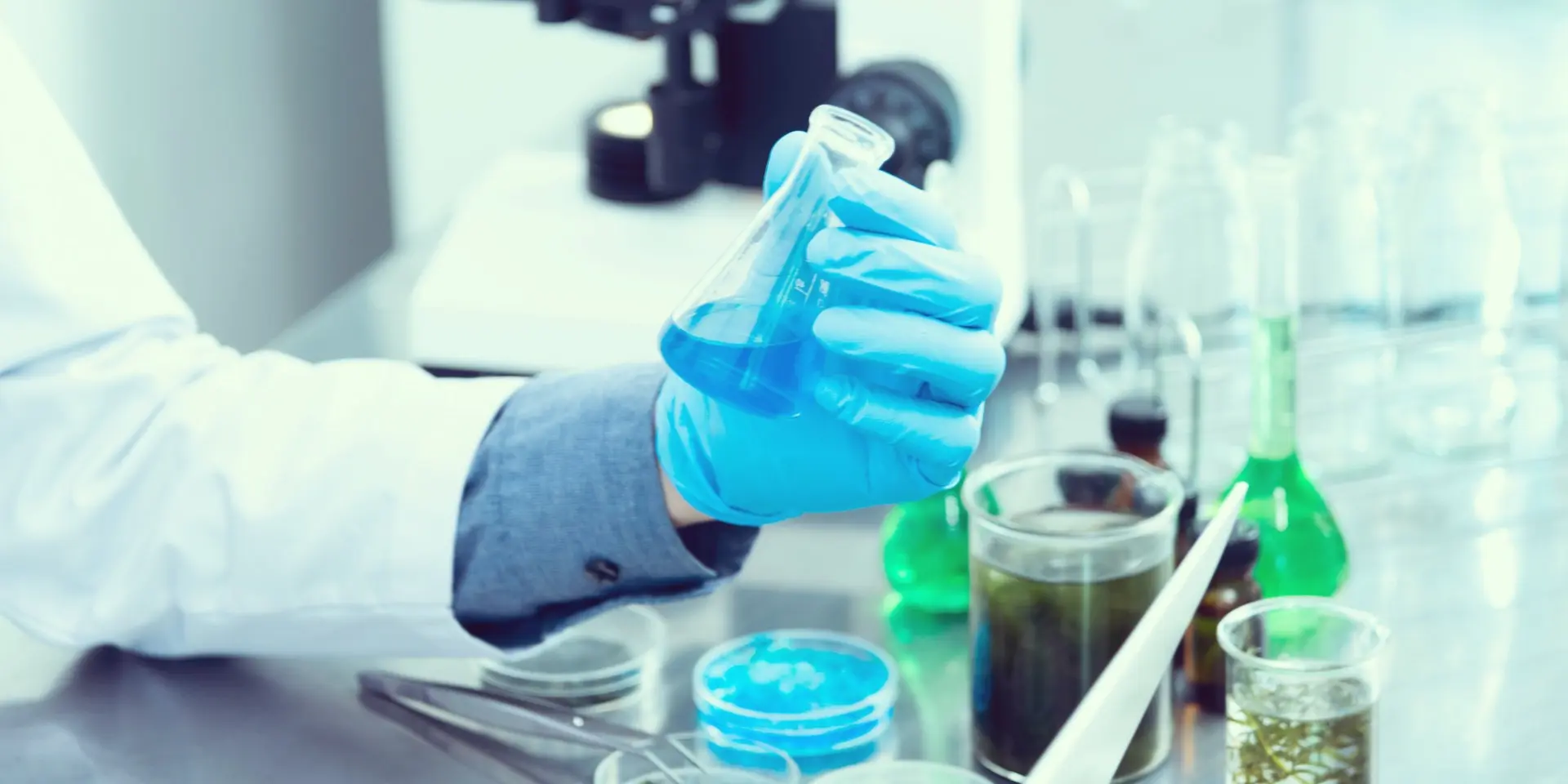 Hand mit Pipette über Probenträgern im Labor
