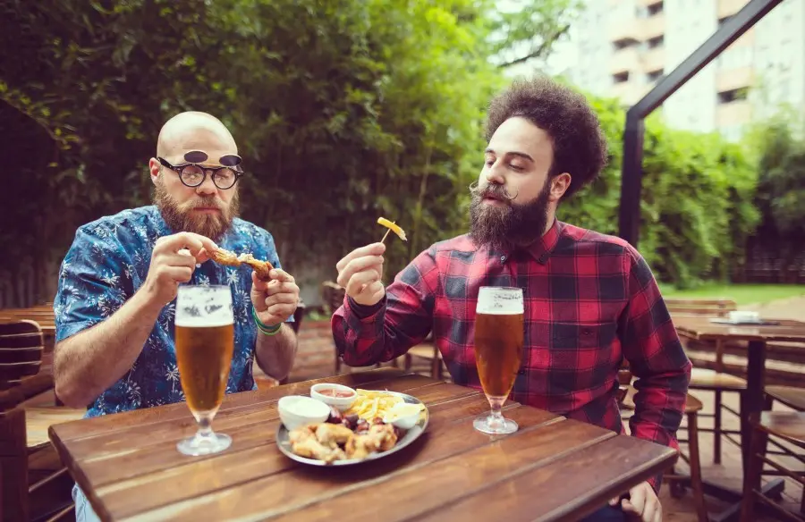 Zwei Männer essen Hähnchen und Pommes an einem Biergartentisch