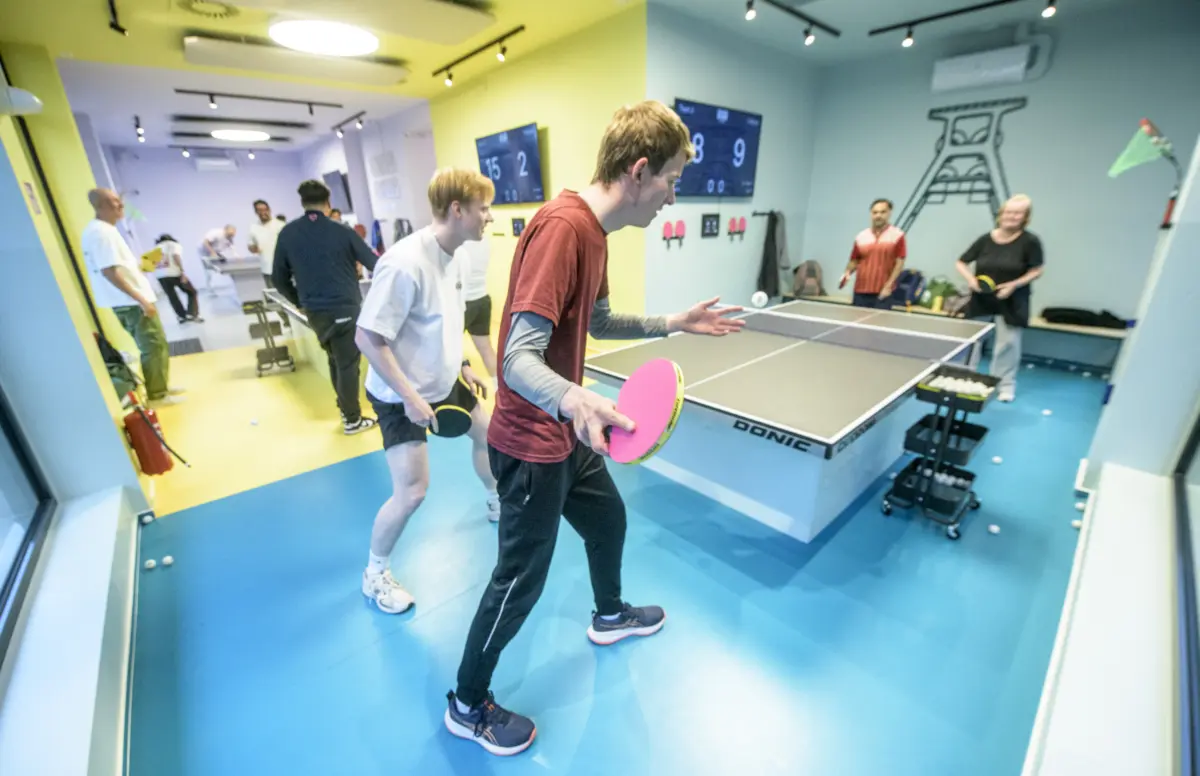 Jugendliche spielen Tischtennis in einer Halle