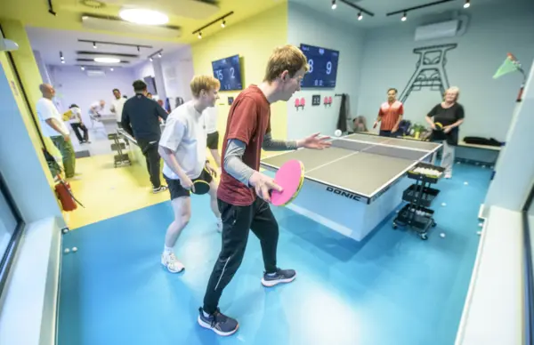Jugendliche spielen Tischtennis in einer Halle