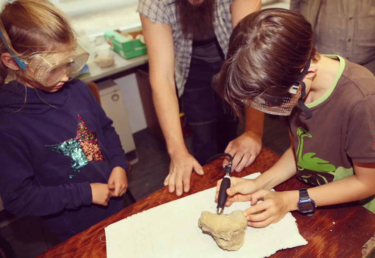 Kinder untersuchen Gesteinsbrocken mit Werkzeug im Mineralien-Museum