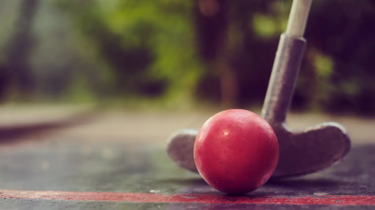 Roter Minigolfball vor einem Schläger