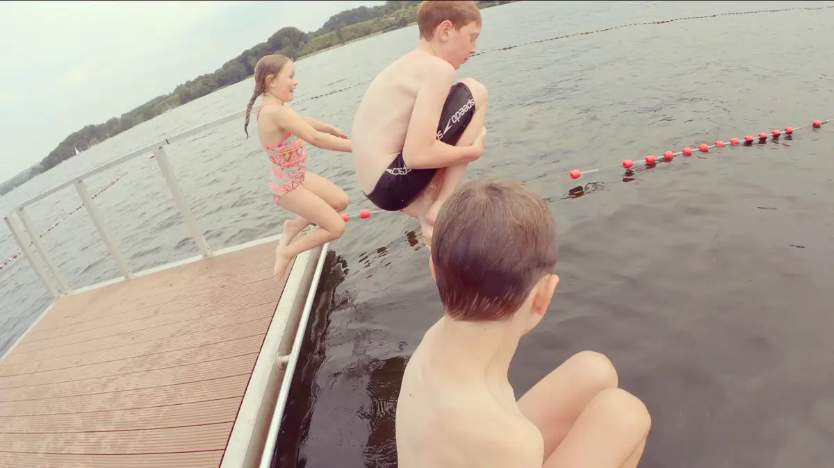 Kinder springen von einem Steg in den Baldeneysee