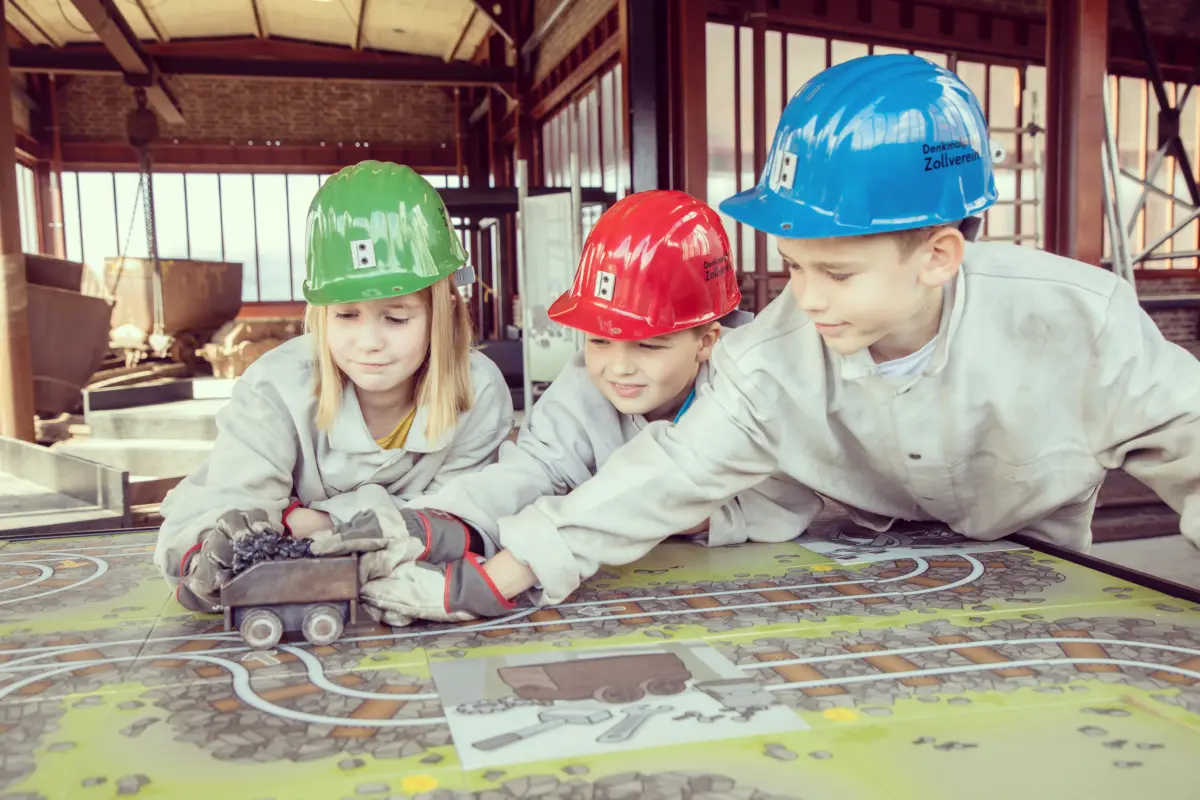 Kinder mit Schutzhelmen am Modell einer Zeche bei einer Zollverein-Führung