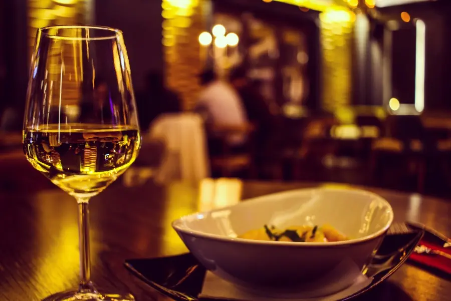 Weißweinglas und Schälchen auf einem Tisch im Restaurant