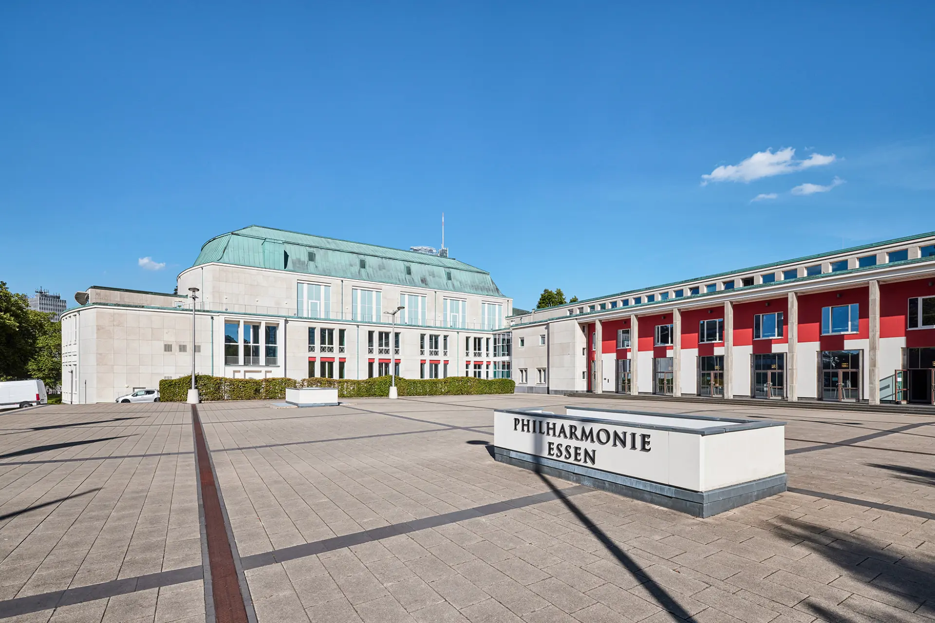 Die Philharmonie Essen mit modernem Vorplatz und blauen Himmel im Hintergrund.