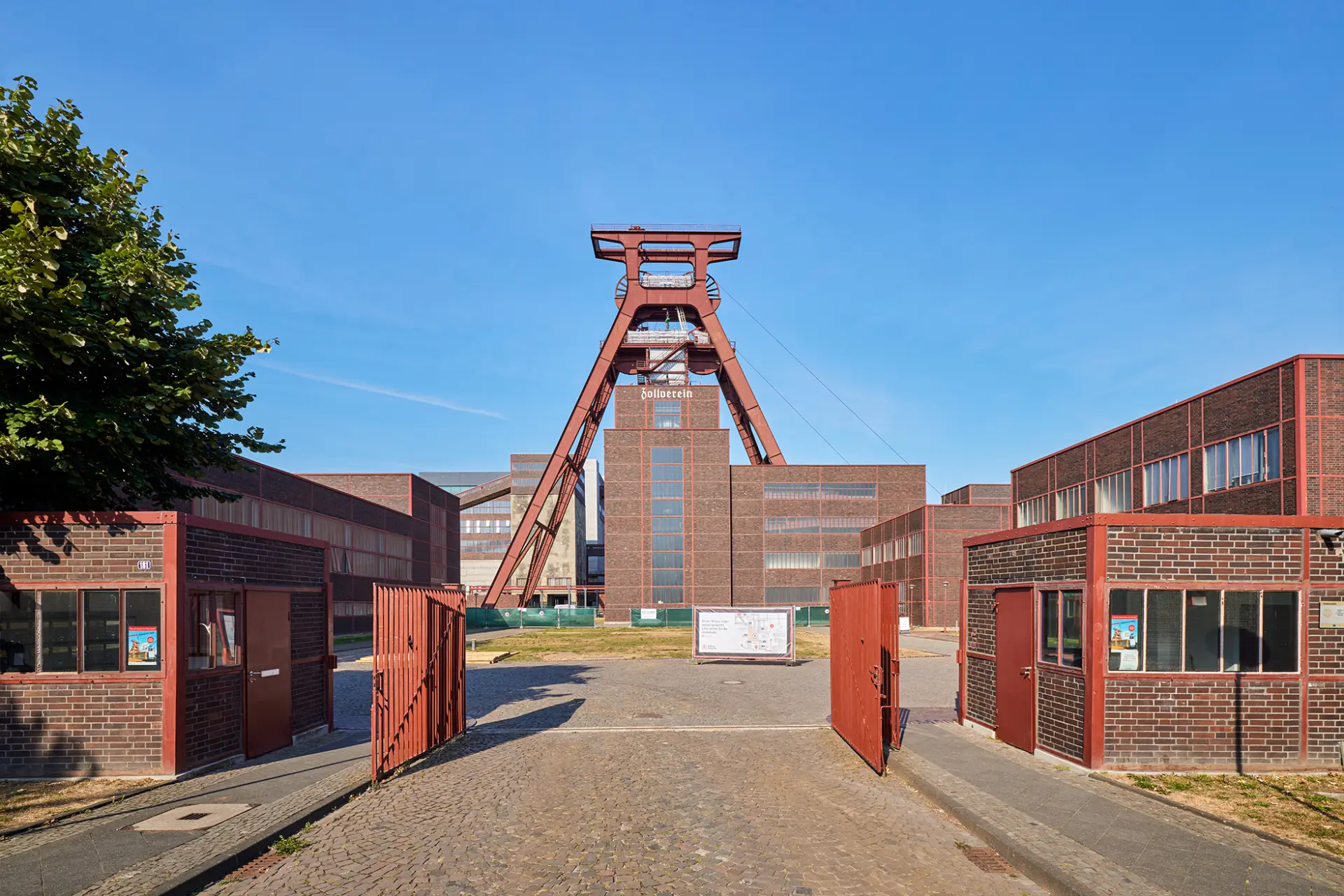 Zechenturm und Backsteingebäude der Zeche Zollverein in Essen unter klarem Himmel.