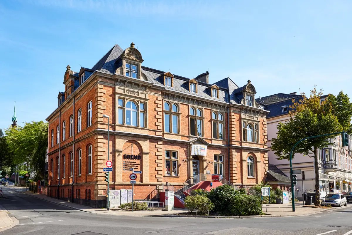 Historisches Backsteingebäude in Essen, mit Giebeln und blauen Fenstern, sonniger Herbsttag.
