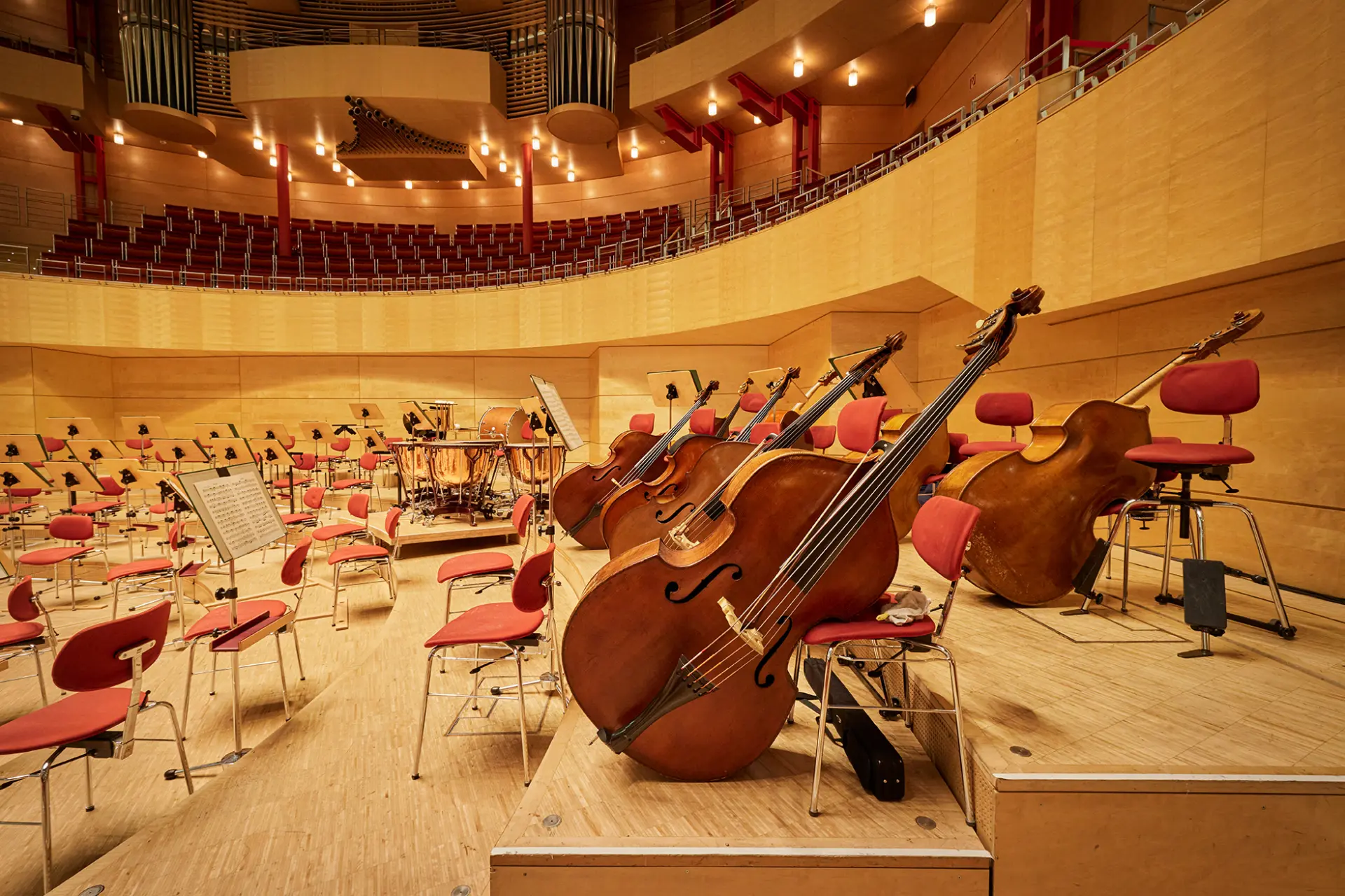 Innenansicht eines modernen Konzertsaals mit leeren Musikerplätzen und Akustik-Instrumenten.