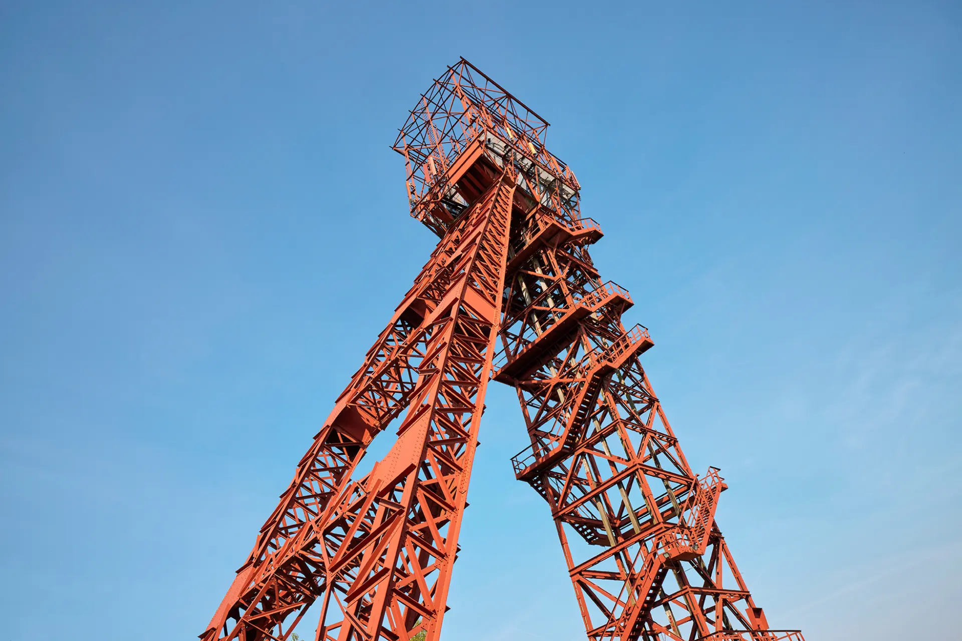 Roter Förderturm der Zeche Bonifacius in Essen erhebt sich markant vor einem klaren blauen Himmel.