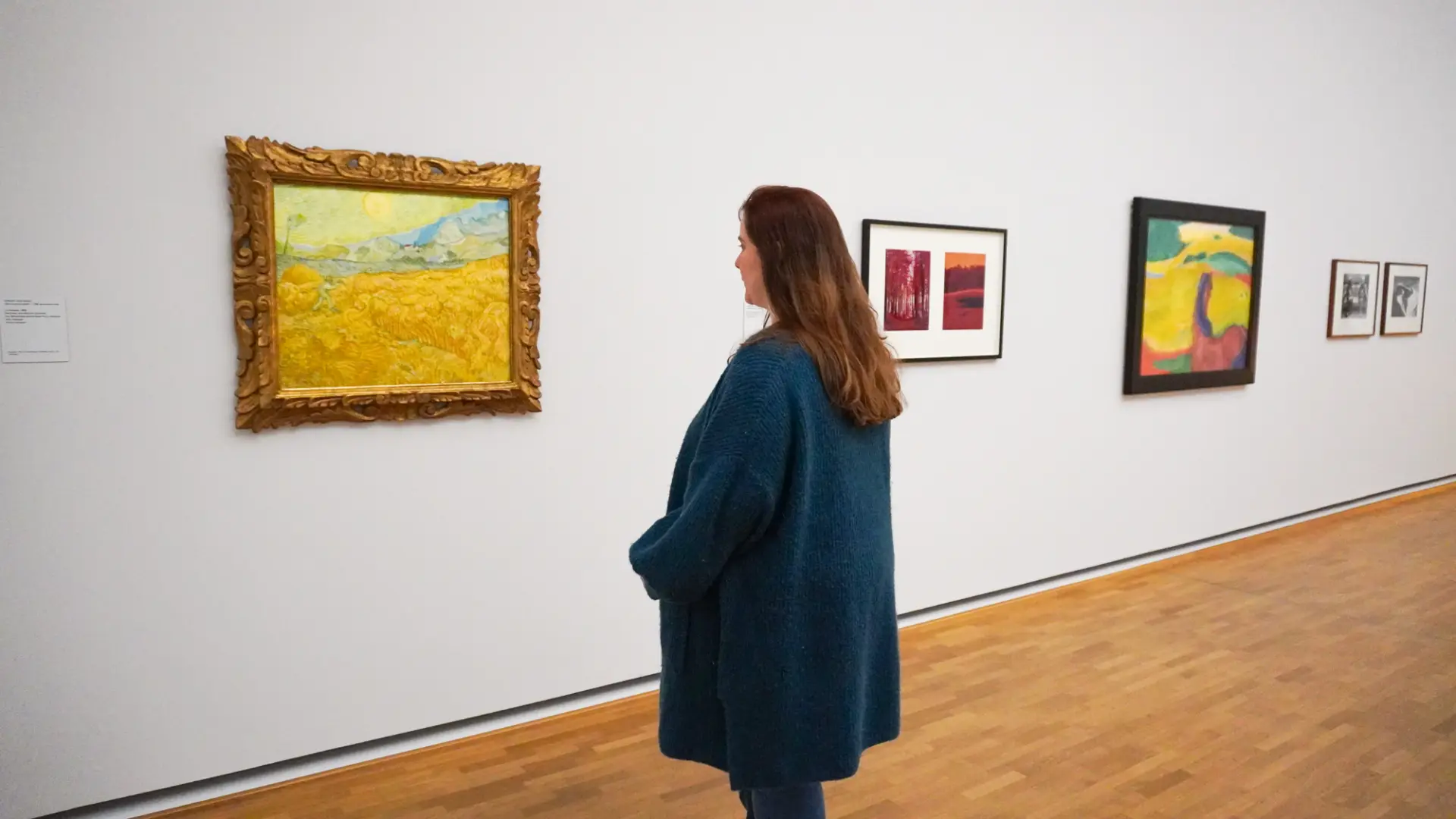 Frau betrachtet Gemälde in einer Kunstgalerie mit Holzfußboden.
