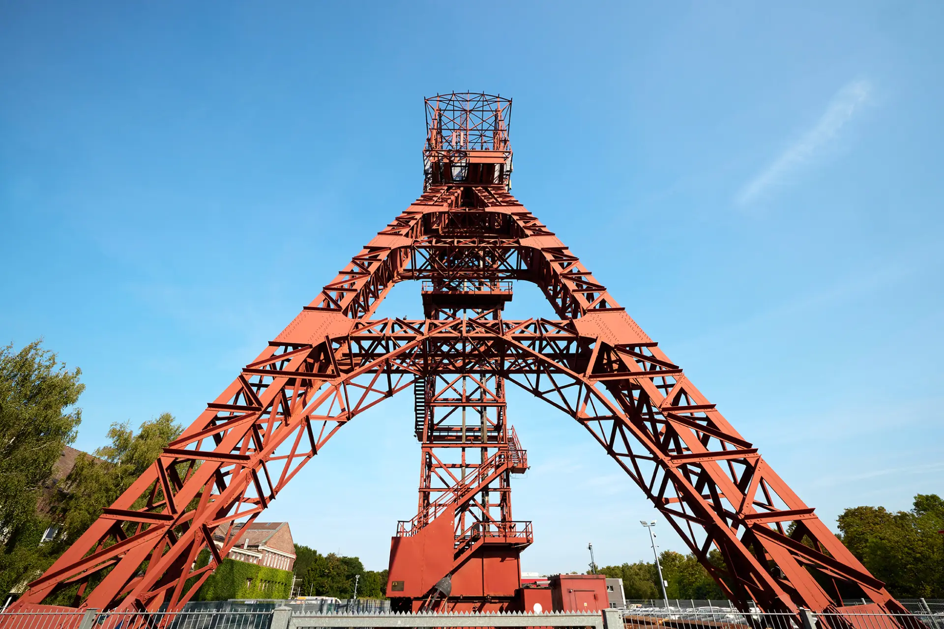 ```html Roter Förderturm der Zeche Zollverein in Essen bei klarem Himmel. ```