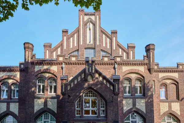 Historisches Gebäude in Essen mit detaillierter neo-gotischer Backsteinfassade und großen Fenstern.