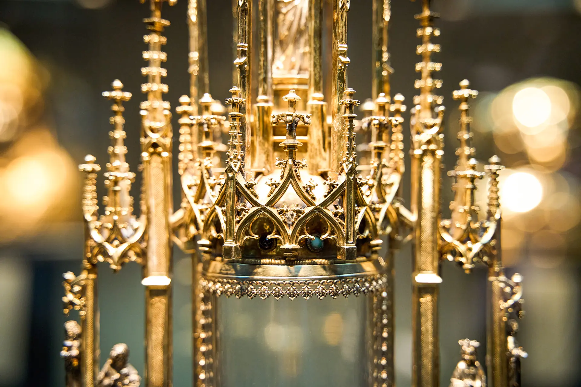 Das Bild zeigt ein filigranes, goldenes Kunstwerk mit komplexen, gotischen Verzierungen und klaren Details.