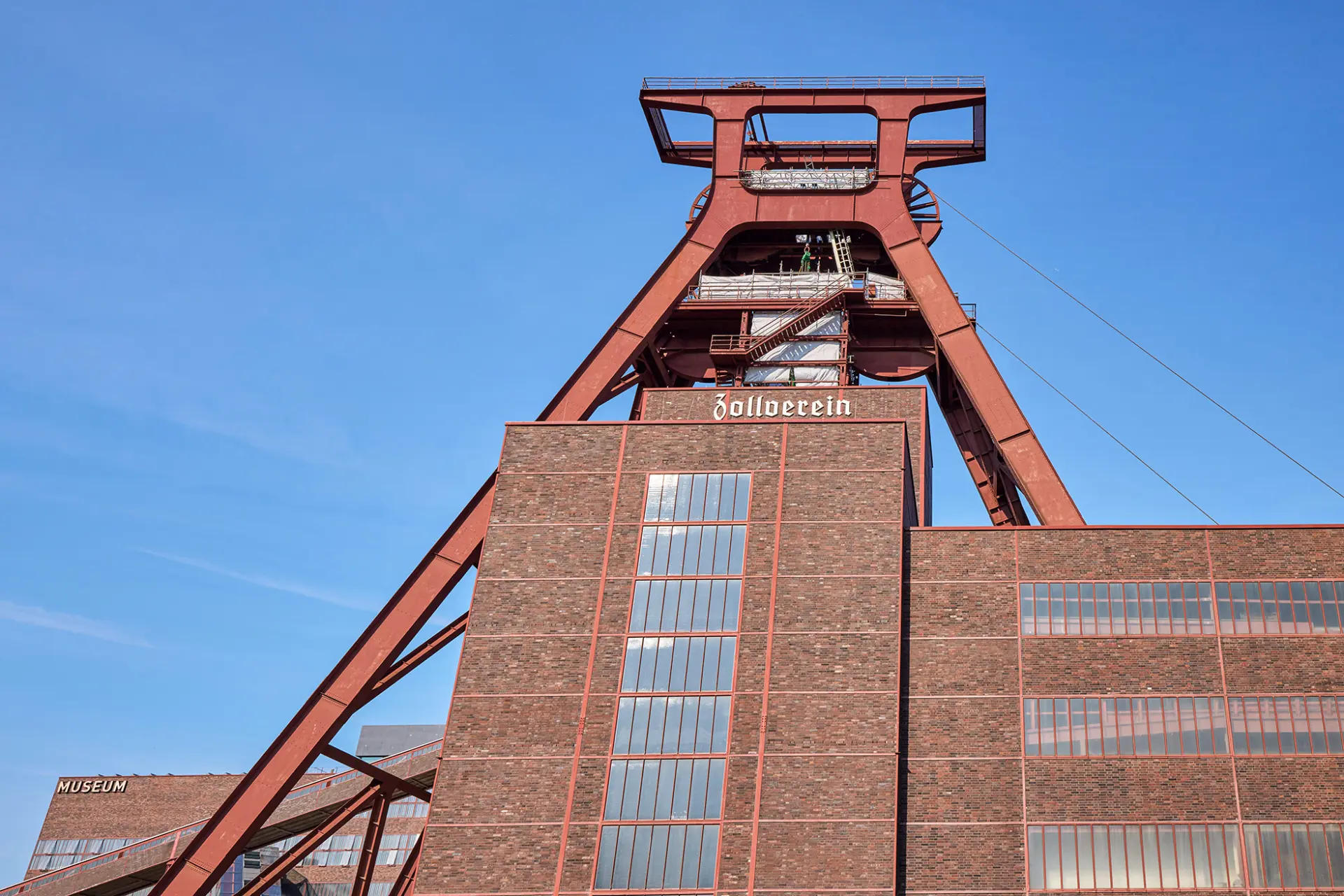 Ehemaliges Steinkohlebergwerk Zollverein in Essen, markant durch roten Förderturm und Backsteinbauten.