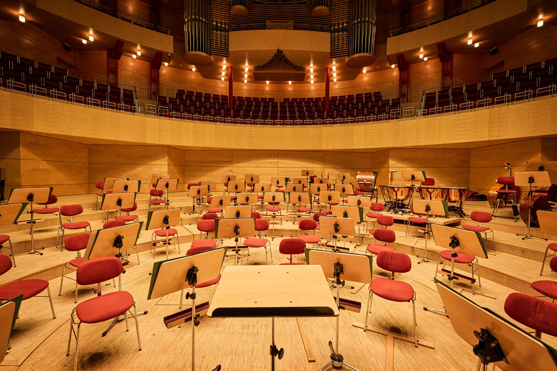 Innenansicht der Philharmonie Essen mit leeren Notenständern und roten Stühlen im Konzertsaal.