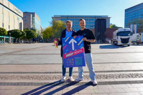 Carsten Hinzer, Brand Activation Lead bei HOLY und EMG-Geschäftsführer Richard Röhrhoff präsentieren auf dem Kennedyplatz die neue Routenbeschilderung des Festi
